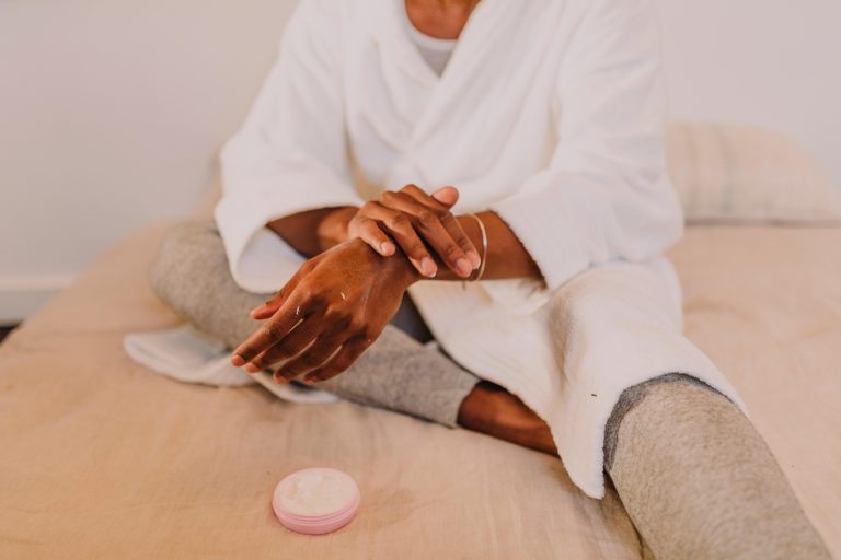 Woman applying lotion in a cozy setting, embracing self-care and relaxation.